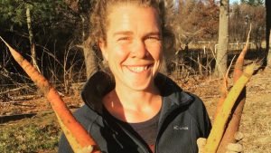 A female farmer holding two carrots